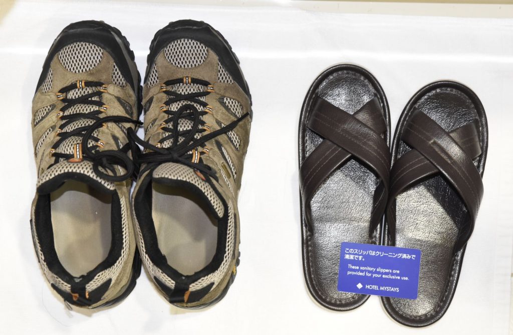 As you take your shoes off even in a Japanese hotel room, the hotel provided sandal slippers for the convenience of guests. The only problem was they were about four sizes too small for my big gaijin feet. My own shoes are at left for comparison. (Richard McGuire photo)