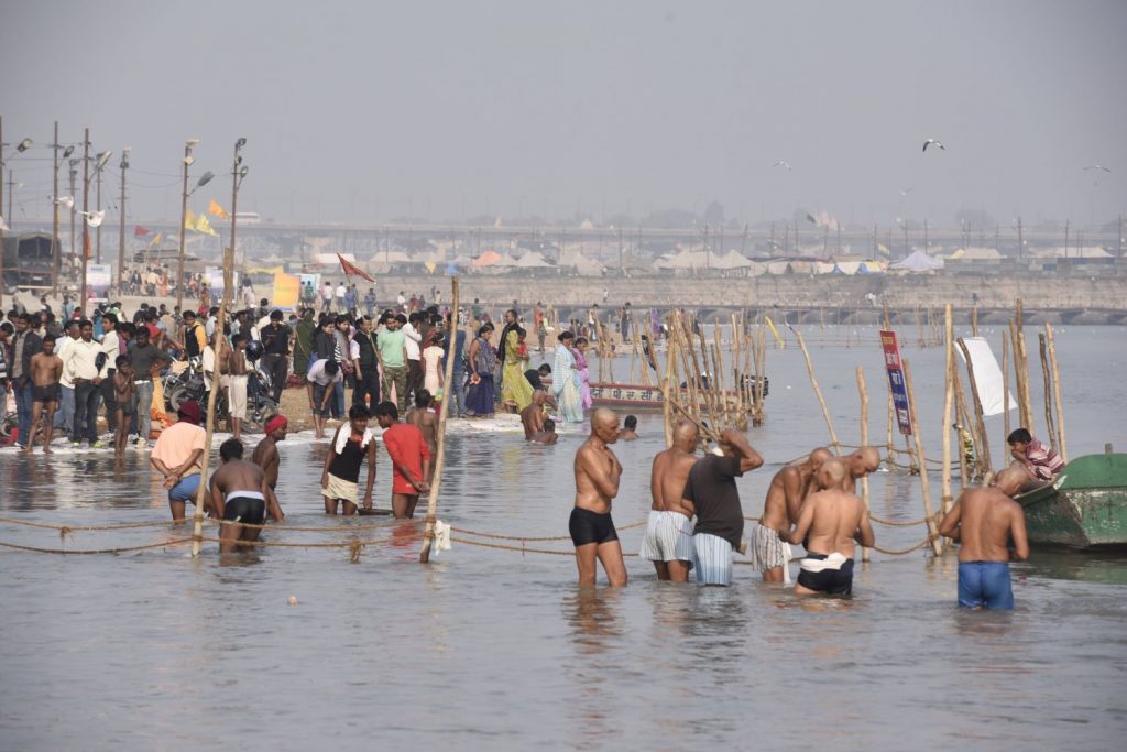 Devout Hindus bathe at Sangam outside Allahabad. A tent city where many of the pilgrims stay is shown in the background. (Richard McGuire photo)