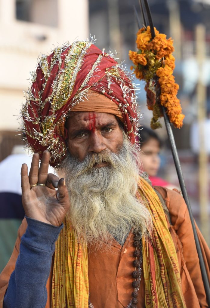 A sadhu or holy man with the marking of Shiva on his forehead carries a trident covered in flowers on the ghats at Varanasi. (Richard McGuire photo)