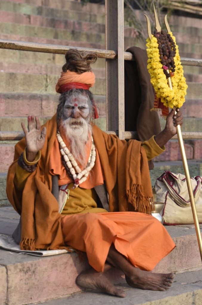 A sadhu devoted to Shiva carries a trident covered in flowers at the ghats in Varanasi. (Richard McGuire photo)