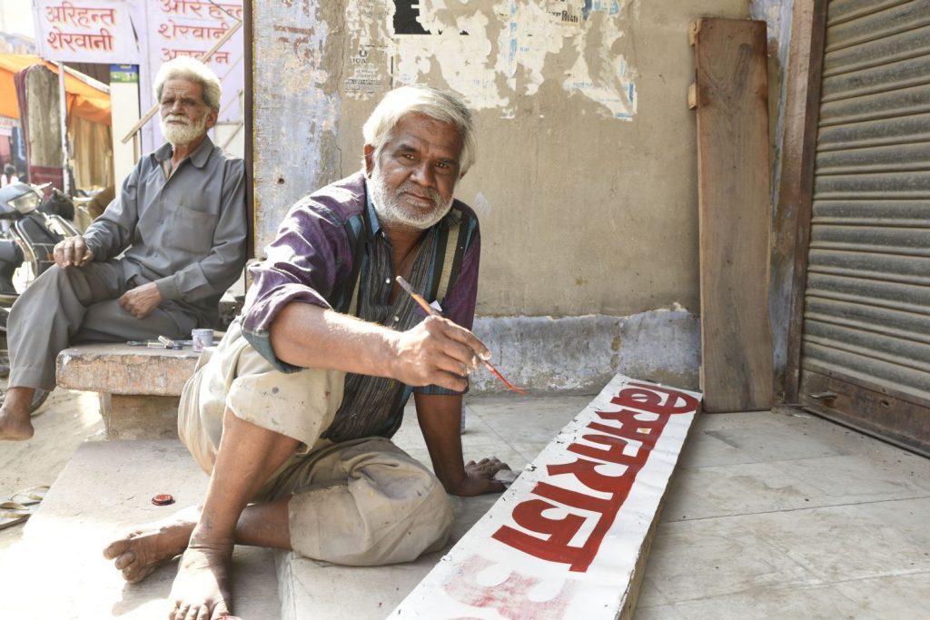 When the man in the background saw my camera, he suggested I should take a photo of his friend who was painting a sign. The sign painter was willing, so I got both me. (Richard McGuire photo)