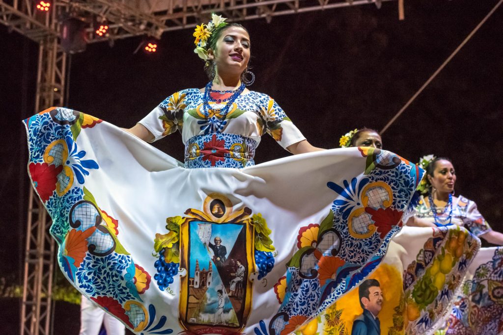 A dancer wears an image of Father Hidalgo on her dress while the dancer to her right wears image of the King of ranchera music, Jose Alfredo Jimenez. (Richard McGuire photo)