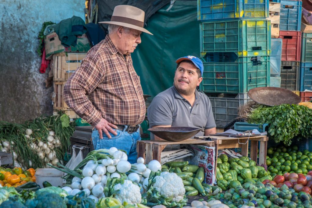 Two men chat in the market in Patzcuaro surrounded by vegetables. (Richard McGuire Photo)