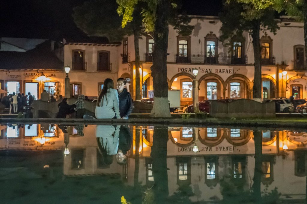 A young couple is reflected in the pool of one of the fountains in Plaza Grande in Patzcuaro. (Richard McGuire photo)